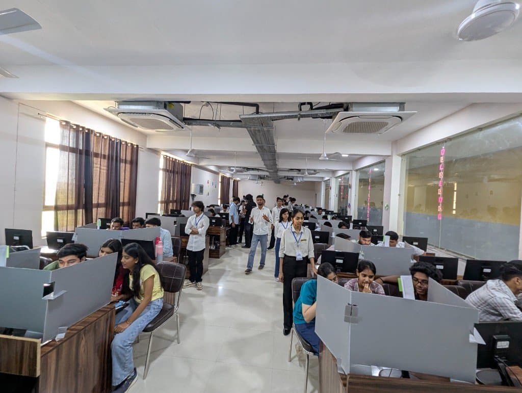 Participants at partitioned desks while organisers stand in the CodeLock aisle.
