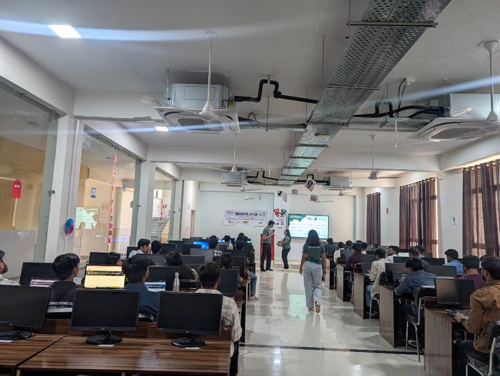 The Hacktoberfest lab in session, with rows of students at computers and organizers near the front screen.